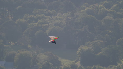 Hang-Glider-flight-go-out-of-frame-right-with-trees-and-city-below,-tandem-hang-gliding