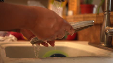 Hands-seen-washing-dishes,-pots-and-pans-under-the-running-water---slow-motion
