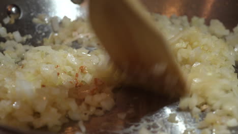 Sautéing-onions-in-a-skillet-and-stirring-them-so-they-don't-burn-with-a-wooden-spatula---close-up