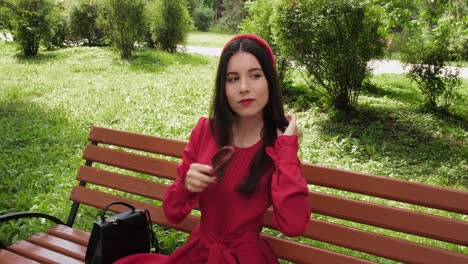 Charming-brunette-sits-on-a-park-bench-and-combs-her-hair