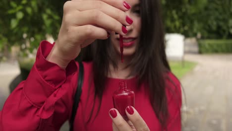 Pretty-pleasing-girl-opens-red-nail-polish