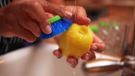 Scrubbing-a-lemon-clean-under-running-tap-water---isolated,-close-up,-slow-motion