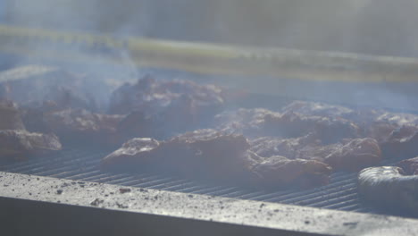 Meat-being-cooked-on-large-barbecue-with-smoke-blowing