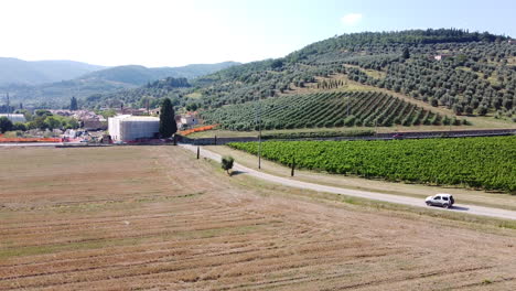 Car-driving-alongside-green-vineyards,-Tuscany,-Italy