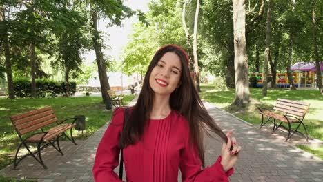 Cheerful-positive-girl-in-red-walks-in-a-beautiful-park