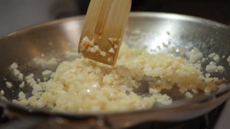 Sautéing-diced-onions-on-a-hot-skillet-using-a-wooden-spatula---slow-motion
