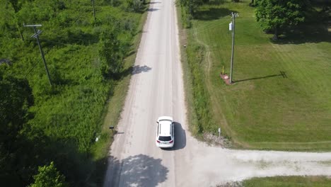 A-white-SUV-drives-down-a-dusty-gravel-path-in-rural-Michigan