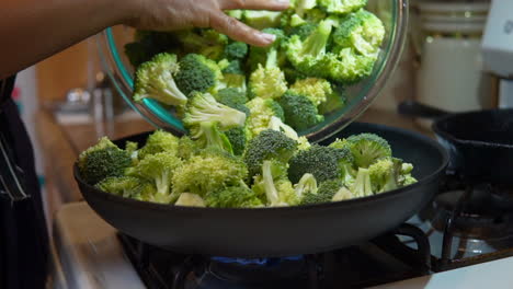 Filling-a-skillet-with-freshly-cut-broccoli-to-cook,-fry-or-steam---slow-motion