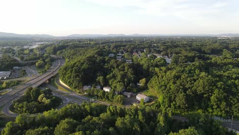 Drone-shot-flying-over-trees-reviling-street-and-highway-60fps
