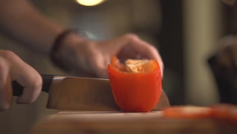 Person-Using-A-Stainless-Knife-And-Cutting-A-Red-Bell-Pepper-Into-Half