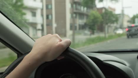 Close-up-of-woman's-hands-on-the-steering-wheel-of-a-driving-car,-following-traffic-in-Montreal