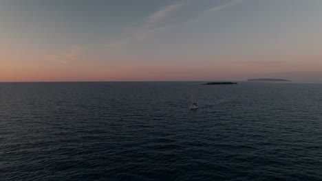 Sailboat-Sailing-Through-A-Calm-Sea-During-A-Beautiful-Sunset---aerial-shot