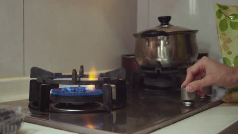 Woman-hand-turns-switch-on-and-ignites-a-gas-cooking-pan