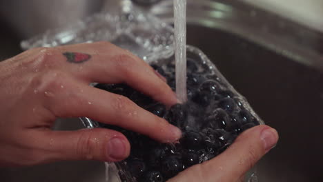 Woman-washes-blueberries-under-tap-water