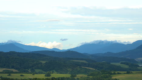 Nubes-Blancas-Moviéndose-Sobre-Un-Paisaje-Montañoso-Lleno-De-Colinas-Durante-Un-Día-Soleado-Nubes-Bajas-Se-Mueven-Sobre-Las-Colinas