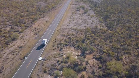 Aerial-track-of-a-big-white-camper-van-driving-through-the-desert-in-the-Mexico-Highway-1