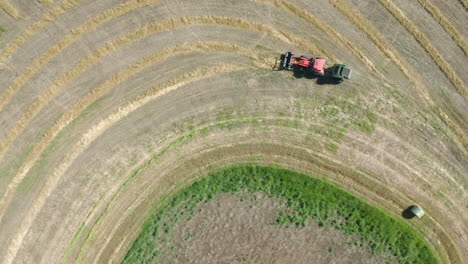 Top-down-Shot-Of-A-Tractor-Baling-Hay-On-The-Farmland-In-Saskatchewan,-Canada-On-A-Sunny-Day---aerial-drone