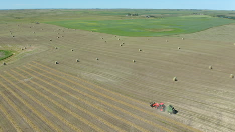 Super-wide-angle-aerial-of-tractor-harvesting-hay-bales-near-Saskatchewan