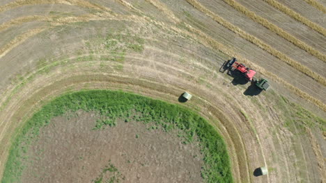 Tractor-Baling-Hay-In-The-Wide-Field-In-Saskatchewan,-Canada---Aerial-Shot