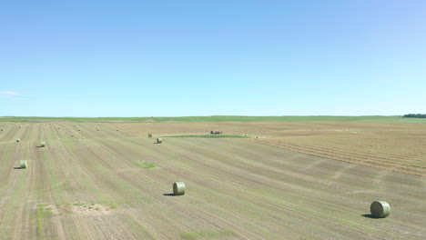 Low-level-aerial-over-vast-fileds-of-hay-bales-during-harvest-season