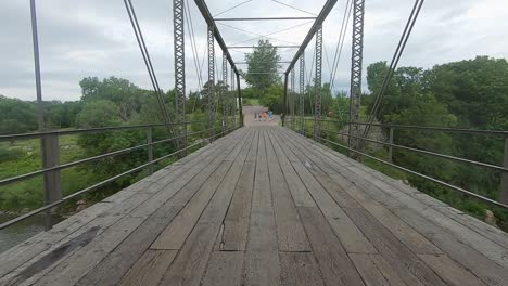 POV-Driving-across-a-turn-of-the-century-truss-bridge-with-a-wooden-deck-over-Split-Rock-Creek-in-Palisades-State-Park-in-rural-South-Dakota,-USA