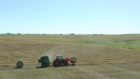 Side-tracking-view-of-a-tractor-dropping-a-bale-of-hay-during-the-harvesting-season