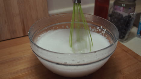 Close-up-on-electronic-whisk-mixing-cake-batter-in-a-glass-bowl