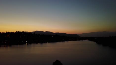 Aerial-rising-shot-of-urban-lake-in-Los-Angeles-during-sunset