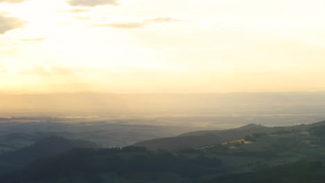 Blick-Auf-Eine-Berglandschaft-Im-Nebel-Während-Des-Sonnenuntergangs-Die-Goldenen-Farben-Der-Hügel-Ziehen-Sich-über-Das-Ganze-Tal