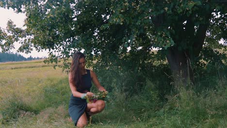 Attractive-Girl-in-Nature-Under-Tree-Making-Floral-Wreath,-Slow-Motion