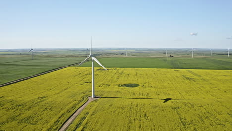 Wind-Turbines-Spinning-On-The-Lush-Farmland-In-Saskatchewan,-Canada-On-A-Sunny-Day---aerial-panning-shot