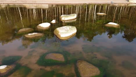 Stones-in-the-water-at-Baltic-sea-coast-Veczemju-klintis-aerial-view-reflection