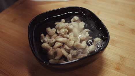 Peanuts-dropping-into-a-black-bowl-with-water-for-soaking