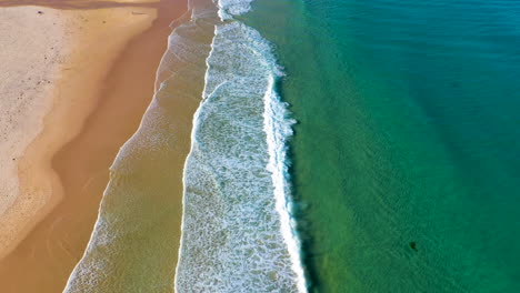Tilting-up-drone-shot-from-surf-to-island-at-Redhead-Beach-Australia