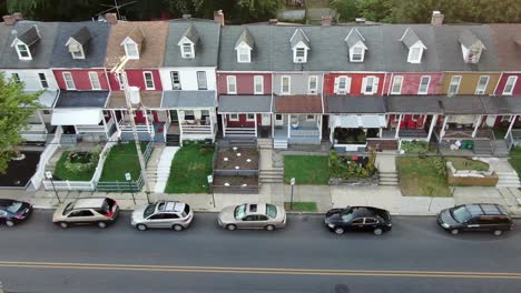 Single-row-of-homes-packed-tightly-together,-cars-parked-on-street,-aerial-truck-shot,-low-income-urban-housing