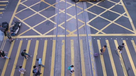 Pedestrians-walk-across-the-road-through-a-zebra-crossing-in-Central-district,-Hong-Kong