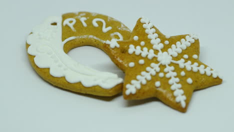 A-hand-lays-a-confectionery-gingerbread-with-white-decoration-on-top-in-the-shape-of-a-star-and-horseshoe-wirh-PF-on-a-white-background