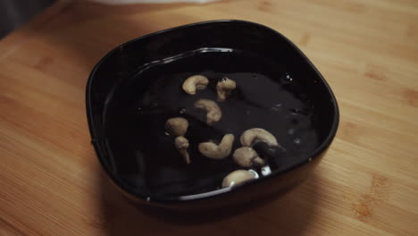 Peanuts-dropping-into-a-black-bowl-with-water-for-soaking