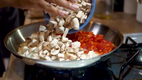Mixing-chopped-onions,-red-peppers-and-mushrooms-in-a-frying-pan-for-a-homemade-vegetarian-meal---slow-motion