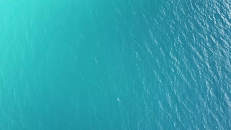 Langsame-Drohne-Aus-Der-Luft-Schwenkt-über-Klares-Blaues-Aqua-Ozeanwasser,-Generische-Grundtextur-Mit-Kleinen-Wellen-Vom-Wind-An-Einem-Sonnigen-Tag