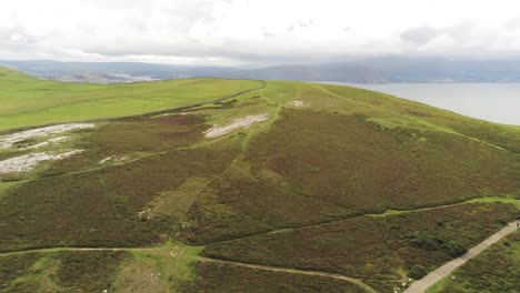 Aerial-view-flying-above-Great-Orme-Llandudno-mountain-valley-ascending-to-rural-landscape-panorama