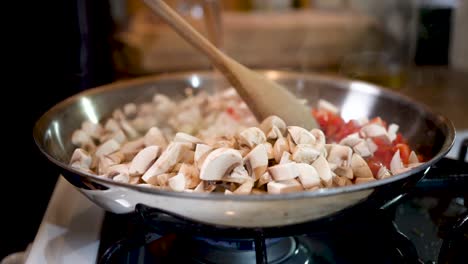 Frying-red-peppers-and-mushrooms-in-a-skillet-on-the-stove-top---slow-motion