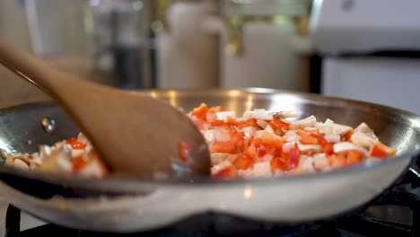 Cooking-a-savory-and-vegetarian-dish-of-red-peppers,-onions-and-mushrooms-in-a-skillet-on-the-stove-top---slow-motion
