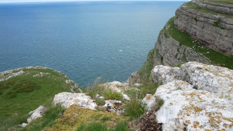 Grassy-rocky-Great-Orme-cliff-edge-mountain-view-dolly-right-overlooking-windy-scenic-sea-view