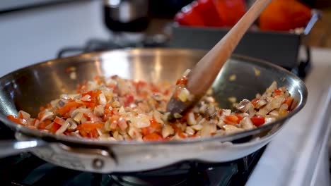 Stirring-a-vegetarian-mixture-of-ingredients-in-a-skillet-on-the-stove-top---slow-motion