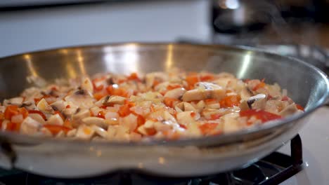 Vegetarian-mixture-of-diced-red-bell-peppers,-onions-and-mushrooms-in-a-steaming-skillet---slow-motion