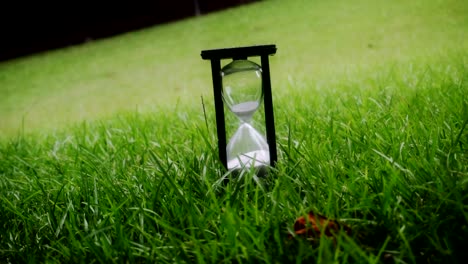 Time-is-running-out-Hourglass-sitting-in-grass-during-a-cloudy-and-rainy-day