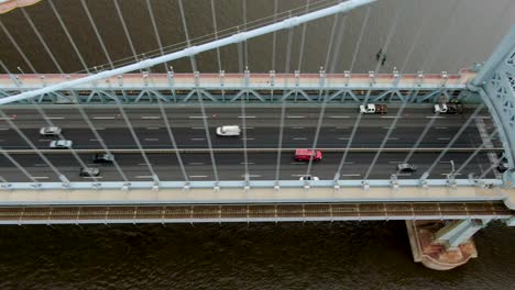 Top-down-aerial-of-traffic-crossing-Ben-Franklin-suspension-bridge-in-Philadelphia-USA,-transportation-and-logistics-theme,-daily-commuter-traffic
