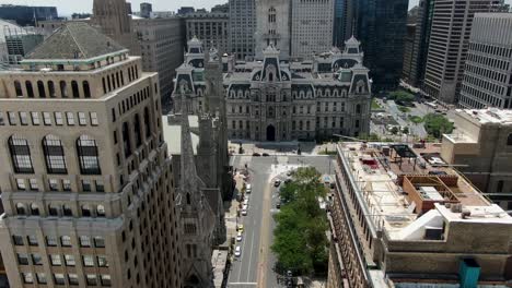 Aerial-tilt-up,-Ben-Franklin-atop-Philadelphia-City-Hall,-view-above-Broad-Street-looking-south