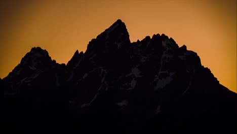 Zeitraffer-Eines-Großen-Berges,-Der-Mit-Dem-Sonnenuntergang-Verblasst-Und-Die-Silhouette-Mit-Einem-Orangefarbenen-Hintergrund-Hinterlässt